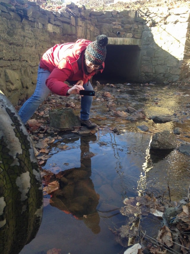 Riverkeeper’s Jen Epstein documents the impact of the pollution on the Sparta Brook. The stormwater outfall pipe is in the foreground at left. (Photo by Dan Shapley)