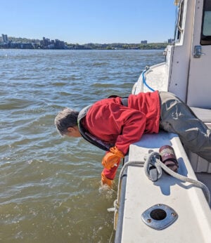 Carol Knudson of Columbia Lamont-Doherty Earth collects a water sample from from a Sea Tow vessel.